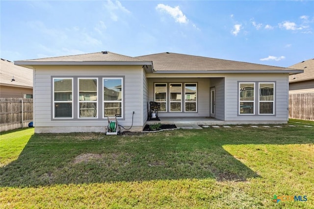 rear view of house with a patio area, a lawn, and fence