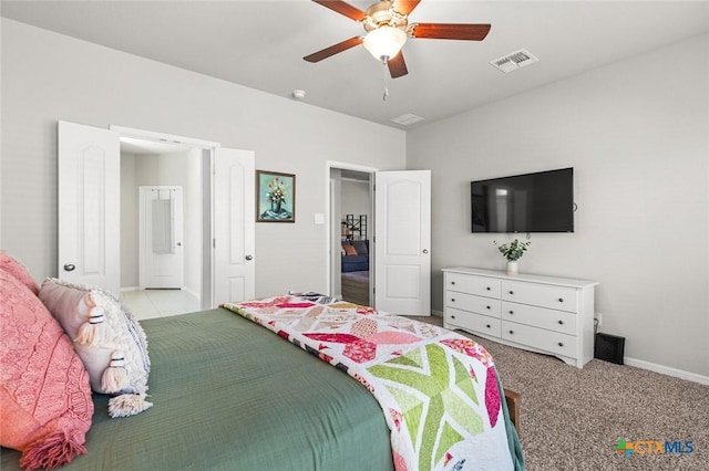 bedroom featuring visible vents, light carpet, ensuite bathroom, a ceiling fan, and baseboards