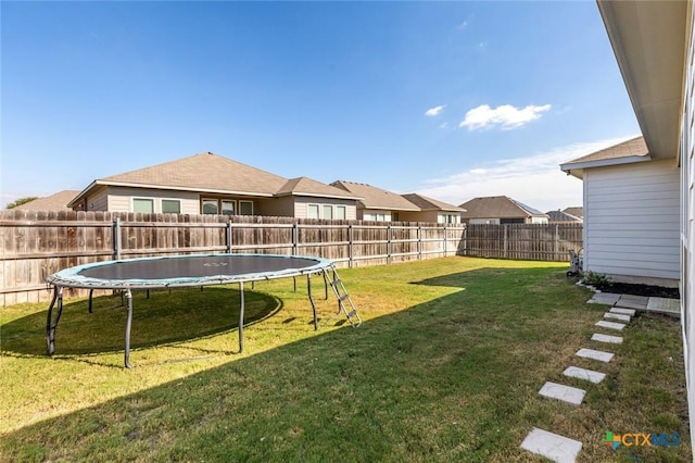 view of yard featuring a trampoline and a fenced backyard