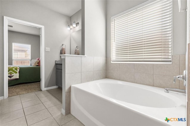 ensuite bathroom featuring a garden tub, connected bathroom, tile patterned flooring, baseboards, and vanity