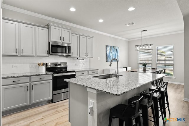 kitchen with visible vents, gray cabinetry, a sink, appliances with stainless steel finishes, and crown molding