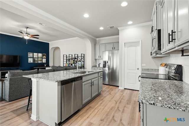 kitchen with visible vents, a sink, open floor plan, arched walkways, and appliances with stainless steel finishes