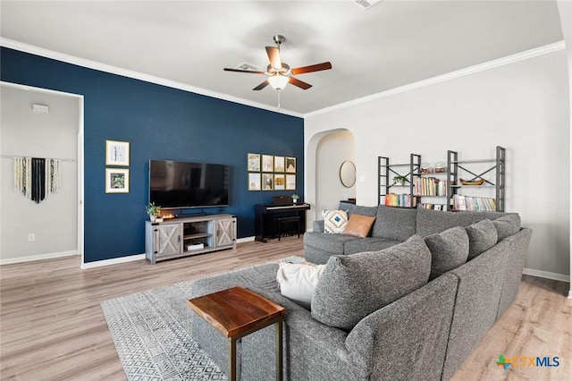 living room with baseboards, arched walkways, light wood finished floors, and ornamental molding