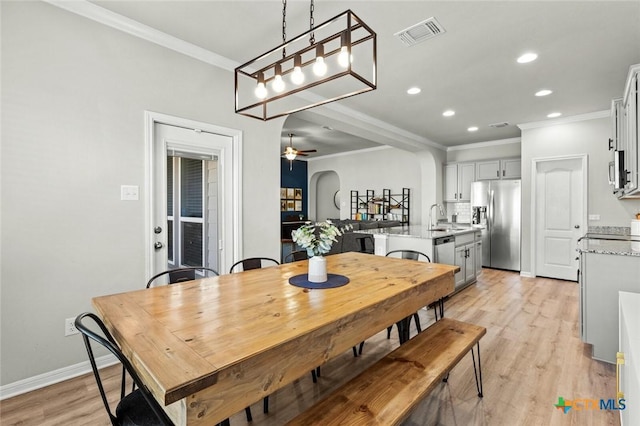 dining area with a ceiling fan, recessed lighting, arched walkways, ornamental molding, and light wood-type flooring