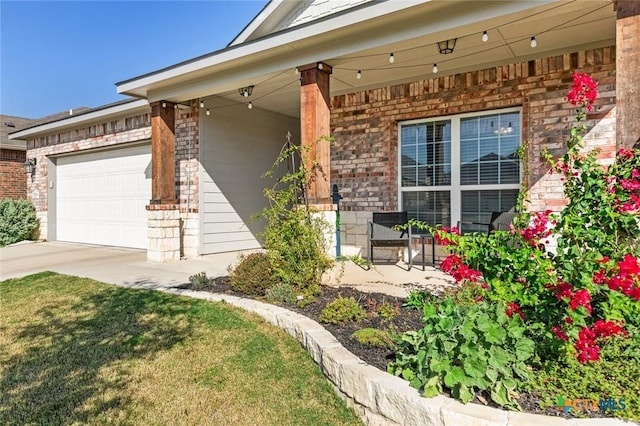 view of exterior entry featuring a porch, an attached garage, brick siding, and concrete driveway