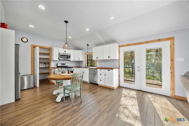 kitchen with white cabinets, pendant lighting, appliances with stainless steel finishes, and hardwood / wood-style floors