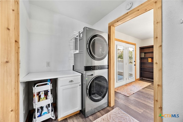 clothes washing area featuring cabinets, dark wood-type flooring, and stacked washer / drying machine