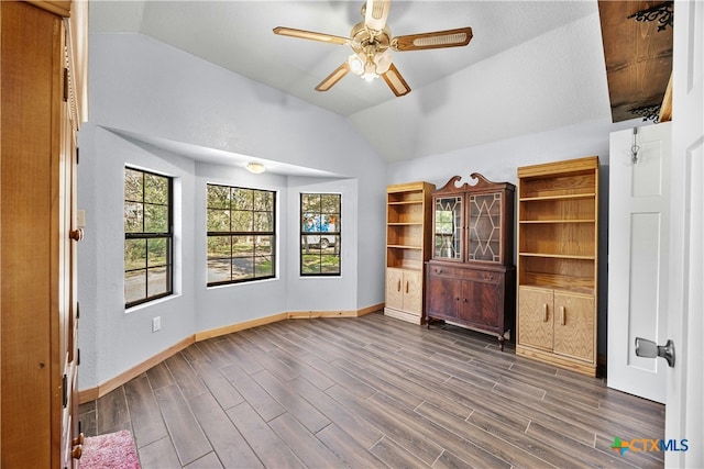 interior space featuring ceiling fan, dark wood-type flooring, and vaulted ceiling