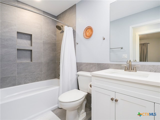 full bathroom with shower / bath combination with curtain, vanity, toilet, and tile walls