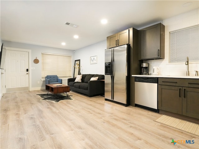 kitchen featuring dark brown cabinetry, sink, appliances with stainless steel finishes, and light hardwood / wood-style flooring