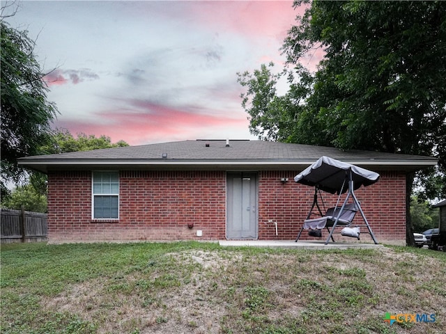 back house at dusk featuring a yard