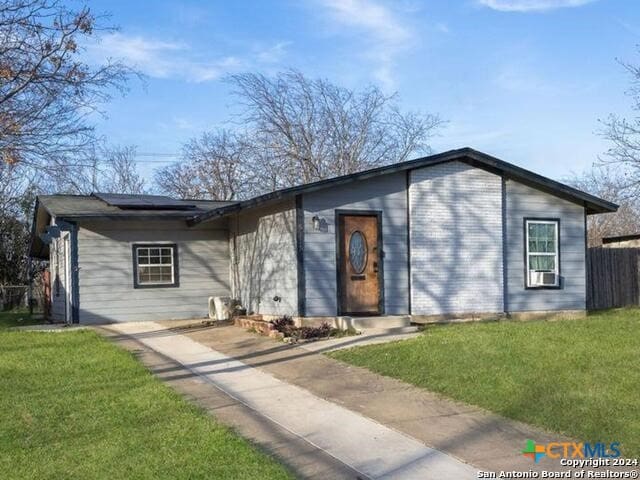 single story home featuring cooling unit and a front lawn