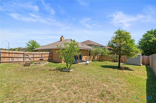 rear view of house with a chimney, a fenced backyard, a yard, a shed, and an outdoor structure