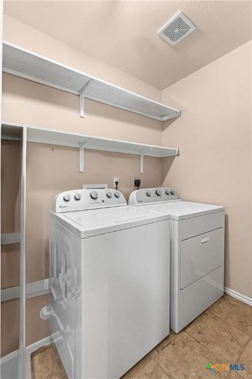 laundry area featuring laundry area, visible vents, light tile patterned flooring, baseboards, and separate washer and dryer