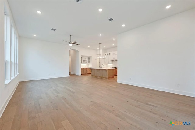 264 Five Mile Creek Way, Kyle, TX 78640 - unfurnished living room featuring baseboards, light wood-type flooring, arched walkways, recessed lighting, and ceiling fan