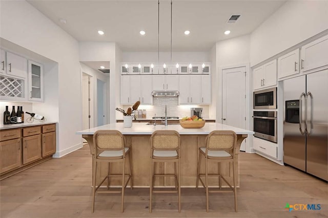 264 Five Mile Creek Way, Kyle, TX 78640 - kitchen with built in appliances, under cabinet range hood, glass insert cabinets, decorative backsplash, and light countertops