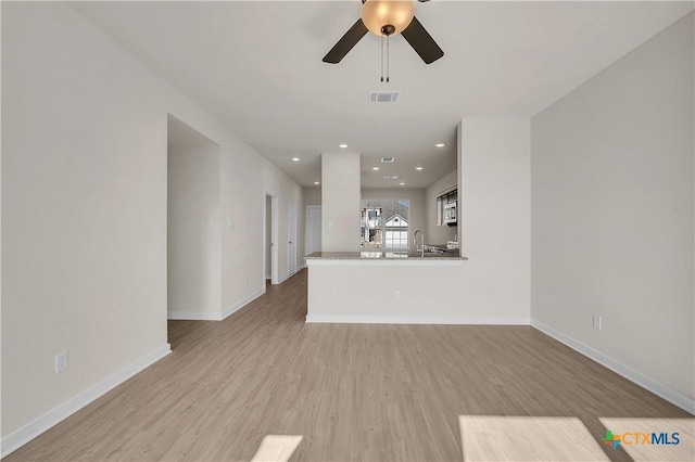 unfurnished living room featuring ceiling fan and light hardwood / wood-style floors