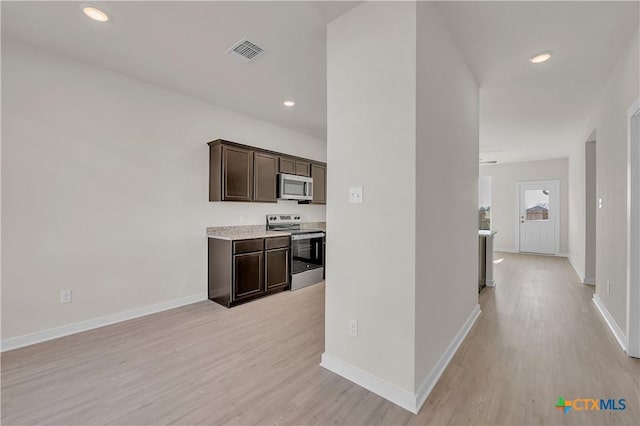 kitchen with light wood-type flooring, dark brown cabinets, and appliances with stainless steel finishes