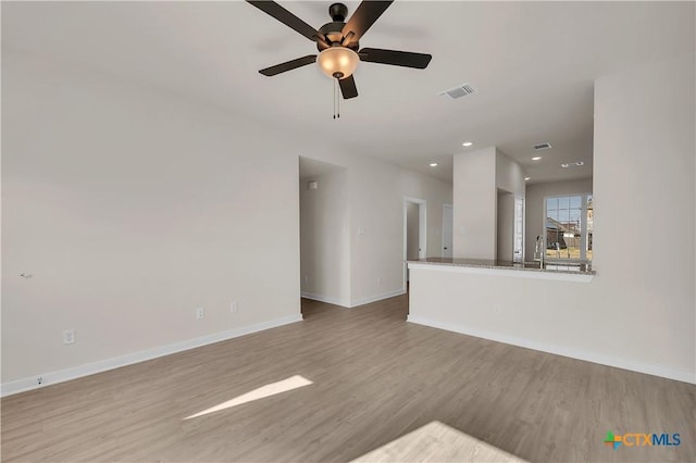 unfurnished living room with ceiling fan, sink, and light hardwood / wood-style flooring