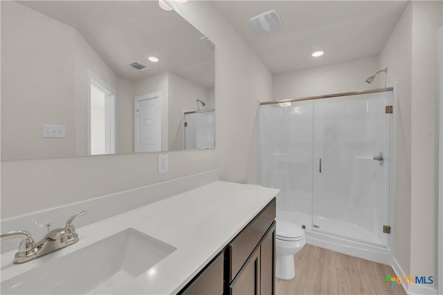 bathroom featuring hardwood / wood-style flooring, vanity, toilet, and an enclosed shower