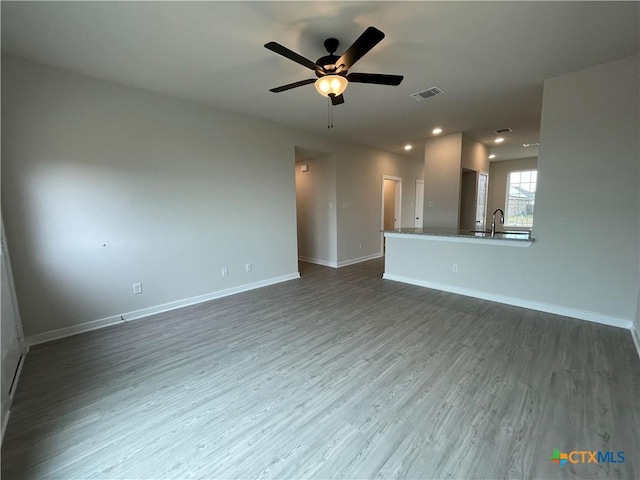 unfurnished living room featuring hardwood / wood-style flooring, sink, and ceiling fan