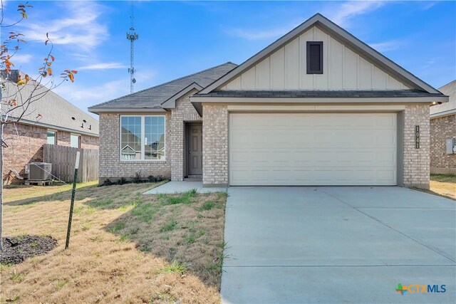 view of front of property with cooling unit, a garage, and a front yard