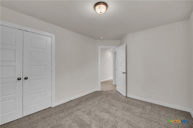 unfurnished bedroom with light colored carpet and a closet