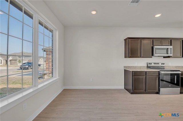 kitchen with stainless steel appliances, dark brown cabinets, and light wood-type flooring