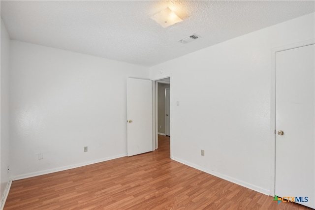 unfurnished bedroom with light hardwood / wood-style flooring and a textured ceiling