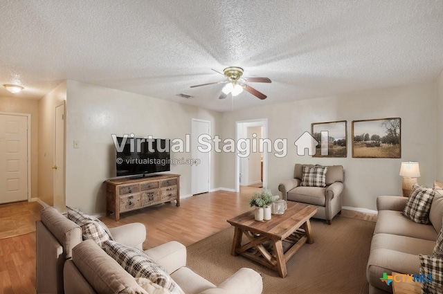 living area featuring a textured ceiling, wood finished floors, visible vents, and ceiling fan