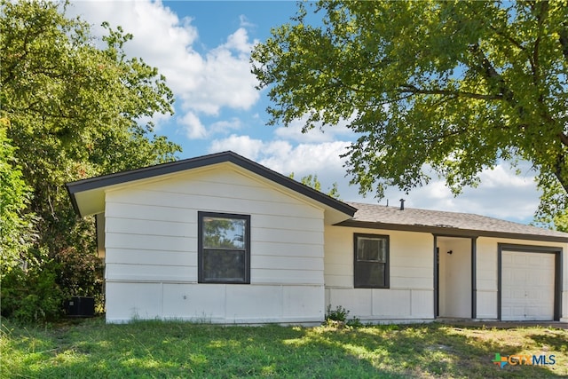 view of property exterior with central AC, a garage, and a lawn