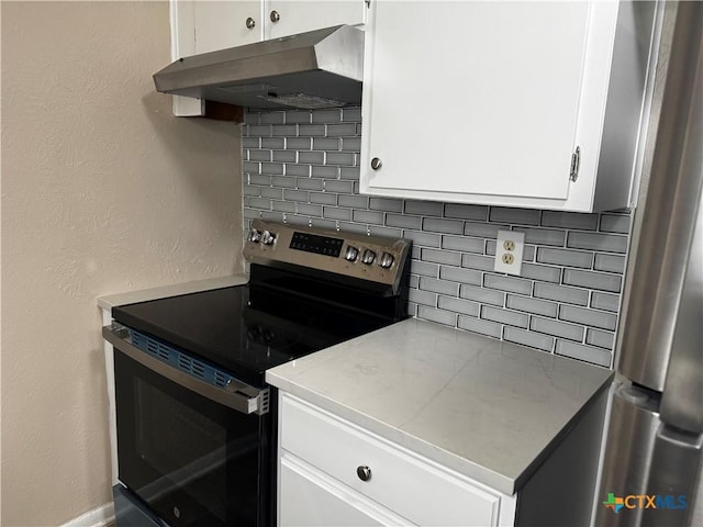 kitchen with under cabinet range hood, decorative backsplash, appliances with stainless steel finishes, and white cabinets