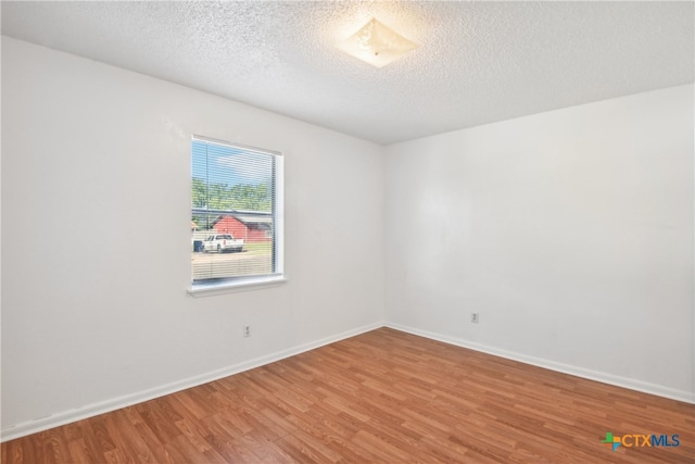 unfurnished room with wood finished floors, baseboards, and a textured ceiling