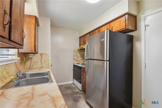 kitchen featuring sink, stainless steel fridge, white range with electric cooktop, backsplash, and a textured ceiling