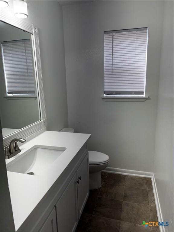 bathroom with toilet, vanity, and baseboards