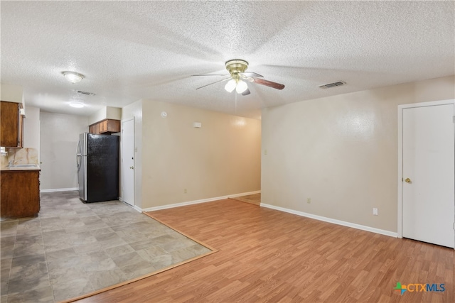 spare room featuring ceiling fan, light hardwood / wood-style floors, and a textured ceiling