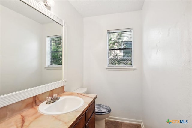 bathroom with vanity, a healthy amount of sunlight, and toilet