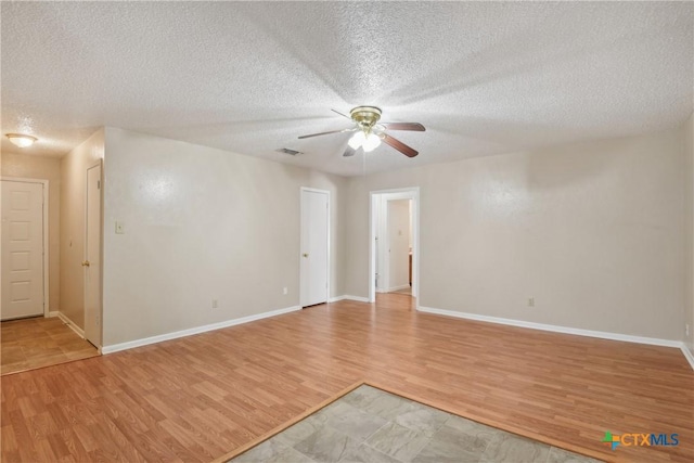 empty room with ceiling fan, light hardwood / wood-style flooring, and a textured ceiling