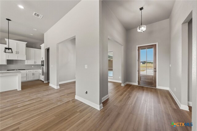 kitchen featuring pendant lighting, light hardwood / wood-style floors, white cabinetry, and a notable chandelier