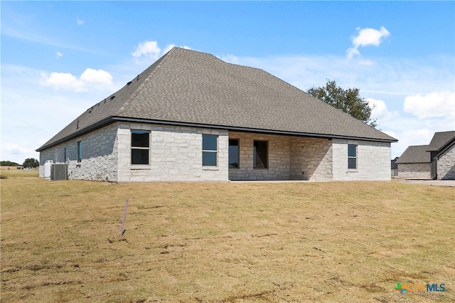 rear view of property featuring a lawn and central AC unit