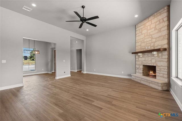 unfurnished living room featuring hardwood / wood-style flooring, ceiling fan, and a fireplace