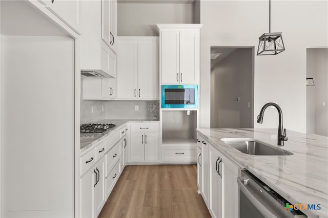 kitchen with appliances with stainless steel finishes, decorative light fixtures, white cabinetry, and sink