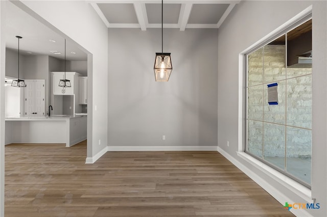 unfurnished dining area featuring beamed ceiling, light hardwood / wood-style floors, a healthy amount of sunlight, and sink