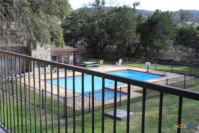 community pool featuring a yard, a patio area, fence, and an outdoor structure