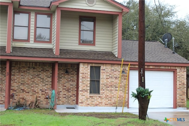 view of front facade with an attached garage, covered porch, brick siding, driveway, and roof with shingles