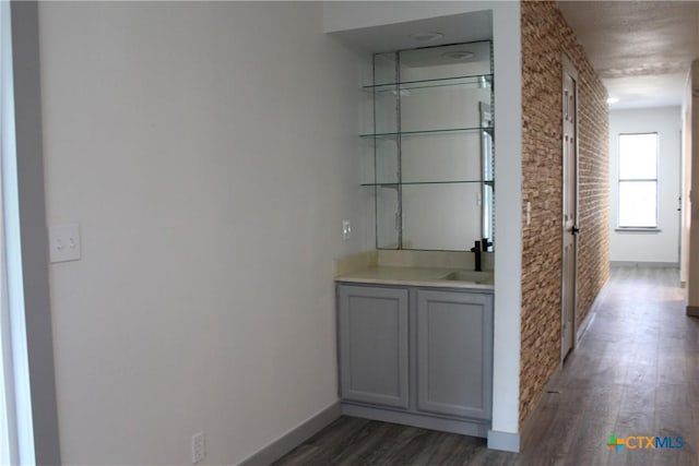 bar with dark wood-style floors, baseboards, and a sink