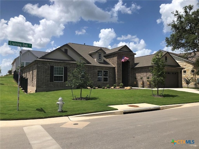 view of front of house featuring a front yard, an attached garage, brick siding, and driveway