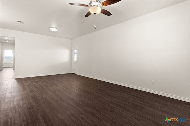 spare room featuring dark wood-style floors, visible vents, ceiling fan, and baseboards