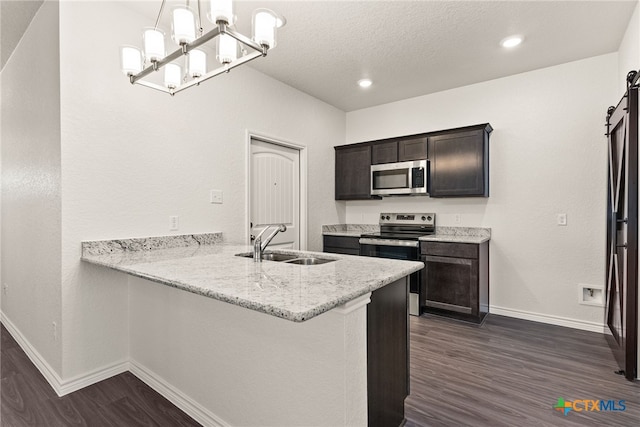 kitchen featuring a sink, a barn door, dark wood-type flooring, and appliances with stainless steel finishes