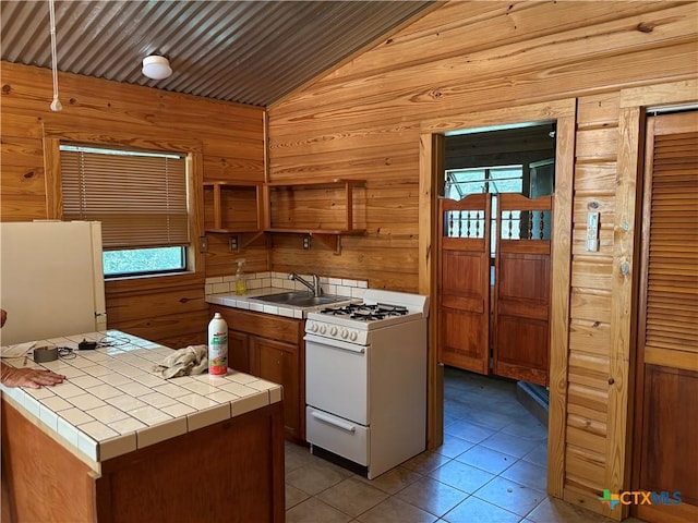 904 Deer Springs Dr, Burnet, TX 78611 - kitchen featuring tile countertops, white appliances, vaulted ceiling, wood walls, and plenty of natural light